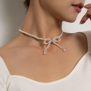 Elegant white pearl choker necklace featuring a trendy rhinestone bow and tassel pendant