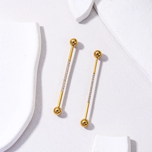 Detailed macro shot of golden industrial piercing bars with sparkling zircon accents