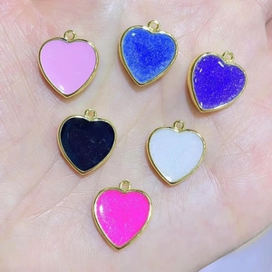 Detail of colorful enamel heart pendants with 18K gold plating held in hand