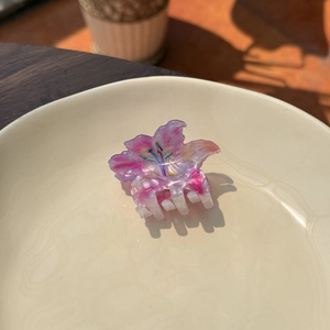 Detailed top view of a lily-shaped purple and pink gradient hair claw on a ceramic plate