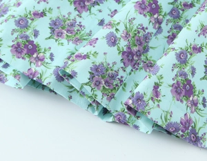 Detailed macro view of sky blue floral poplin fabric with purple flower print patterns