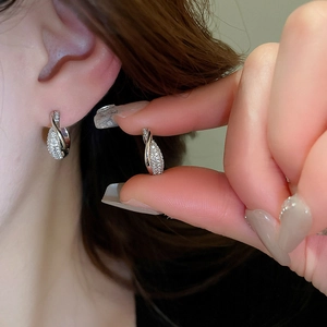 Detail of silver waterdrop earrings with full pavé crystals on ear showing premium shine