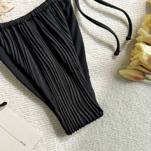 Close-up of black pleated high-waist bikini bottoms with thin side-tie detailing