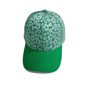 Detailed top view of a light green floral baseball cap with daisy pattern and green brim