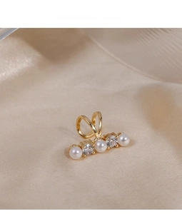 Detail view of gold ear cuff featuring elegant pearls and cubic zirconia on silk fabric