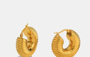 Macro detail of gold-plated twisted hoop earrings with polished croissant texture style