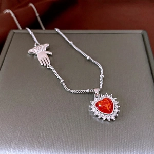 Silver necklace with red heart pendant and palm charm on a luxury display