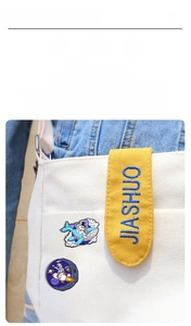 Detail of creative astronaut enamel pins attached to a white canvas bag for decoration