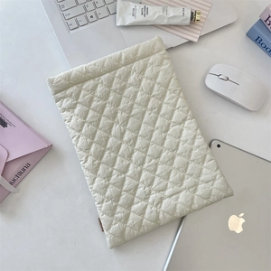 Close-up of beige quilted diamond pattern laptop sleeve in a minimalist desk setting