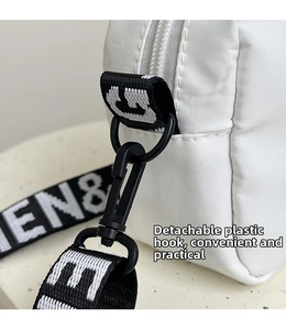 Detail of white nylon bag featuring a detachable plastic hook and woven lettered strap