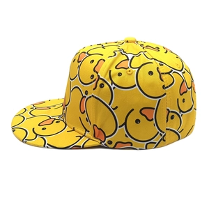 Detailed side view of yellow snapback hat featuring all-over cartoon duck print