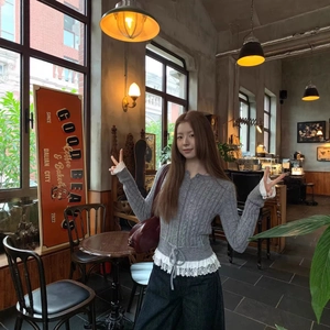 Gray knit cardigan with delicate white lace trim and drawstring waist in a cozy cafe setting