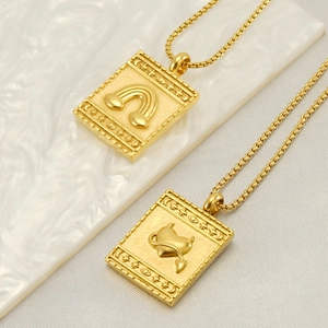 Detail of vintage gold-plated square pendants with embossed rainbow and winged heart