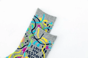 Detail view of gray cotton crew socks with colorful floral patterns and humorous text