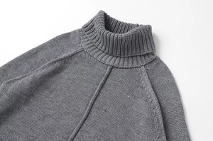 Detail of grey turtleneck sweater featuring rib knit texture and raglan sleeve stitching