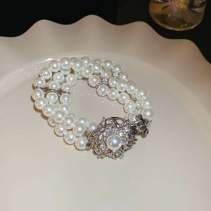 Détail d'un bracelet de perles multicouches avec fermoir fleur étincelant sur plat blanc