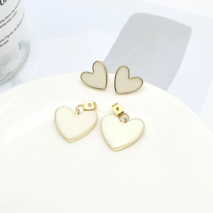 S925 silver heart stud earrings with cream enamel and gold rim on a display plate