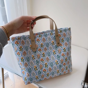 Vue détaillée du sac cabas en coton à imprimé floral avec des poignées en cuir camel