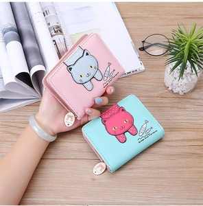 Close-up of pink and blue folding wallets with cute cat print on a wooden desk