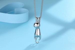 Detailed view of long cute cat pendant necklace with polished silver finish on blue background