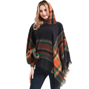 Close-up detail of checkered knit poncho featuring orange and green stripes with tassel fringe
