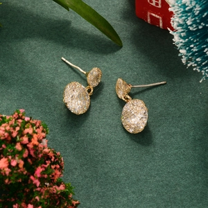 Detail of gold mesh earrings featuring sparkling crystals on a forest green background