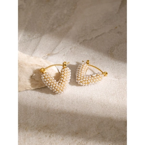 Vue macro de boucles d'oreilles en forme de cœur en or 18k avec perles sur socle en pierre