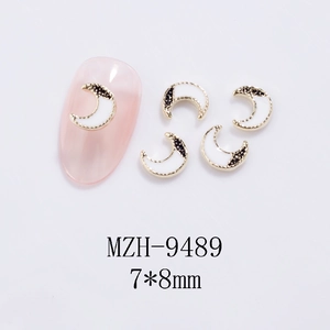 Detailed view of crescent moon nail charms with gold metallic frames on pink manicure