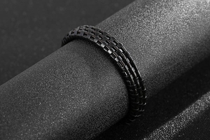 Macro shot of men's matte black titanium steel ring with three-row woven texture