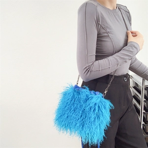 Detail of blue faux sheepskin bucket bag with black metal chain strap on model