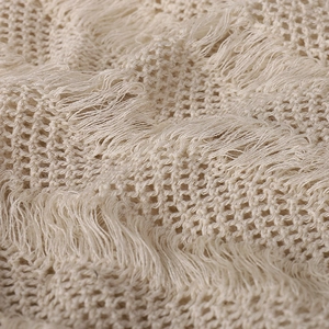 Détail macro du tissu en maille crème avec glands décoratifs pour un bonnet bohème
