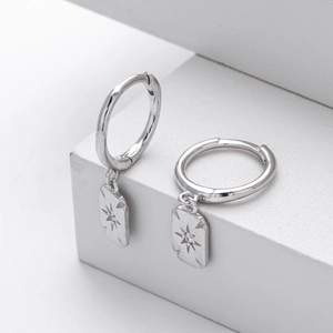 Macro detail of silver S925 star hoop earrings with zircon stones on a white stand