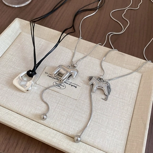 Close-up of metallic brushed horse hollow pendant and bag charms on silver snake chains