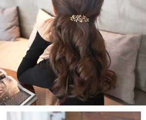 Close-up of golden floral hair clip with pearls and rhinestones on hair