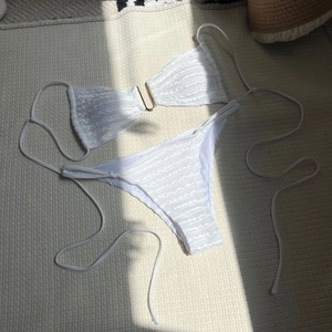 Close-up of white textured bikini fabric with golden U-shaped hardware decoration