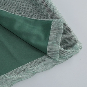 Détail du tissu en maille vert foncé et des coutures invisibles de la robe de soirée