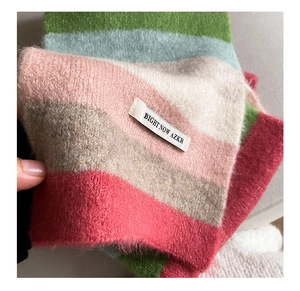 Detailed macro view of soft rainbow striped mohair scarf texture and brand logo label