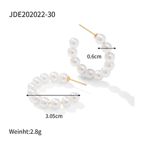 Detail view of gold C-shape hoop earrings with 3.05cm diameter and round pearls