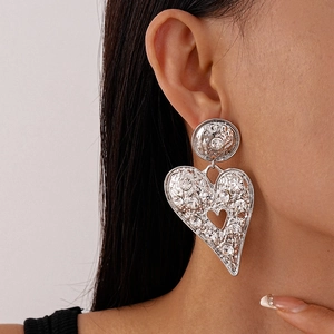 Detail view of silver heart earrings with hammered texture and sparkling rhinestones