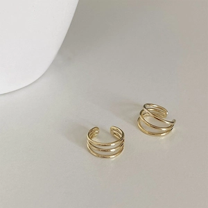 Detail view of gold multi-layer ear cuffs featuring a modern triple hoop open ring design