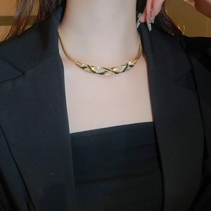 Detail of curved gold necklace featuring black enamel and sparkling diamond-set patterns