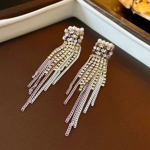 Detail von eleganten Perlen- und violetten Kristall-Quastenohrringen auf Holz