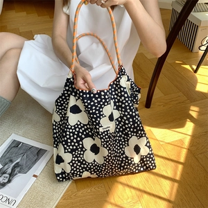 Detail of floral canvas tote bag with woven dual-tone handles in a bright minimalist setting