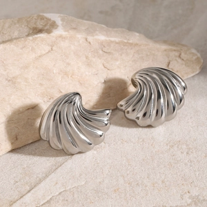 Detailed view of silver shell-shaped titanium steel earring on a textured stone surface