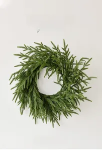 Close-up of lifelike green Norfolk pine wreath with dense needles on white background