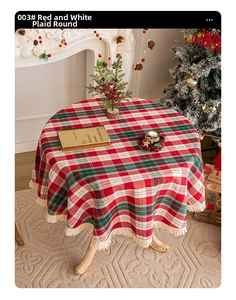 Detail of round red and white plaid tablecloth with cream tassels in festive setting