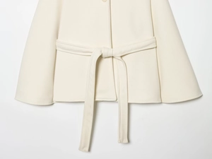 Detail shot of a beige wool blend cape coat showing waist tie belt and texture