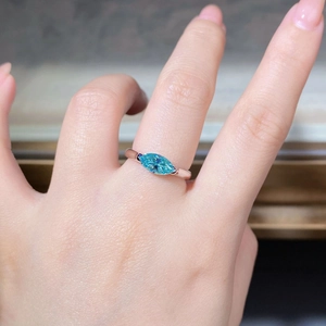 Close-up of marquise-cut sky blue gemstone on a sterling silver ring worn on finger