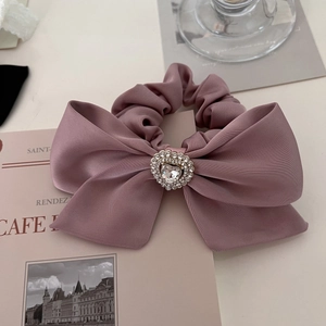 Detailed shot of pink satin bow scrunchie with a sparkling rhinestone heart center