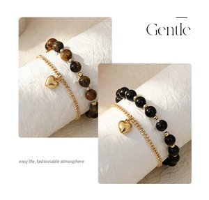 Detail of tiger eye and black obsidian beaded bracelets with gold heart charms